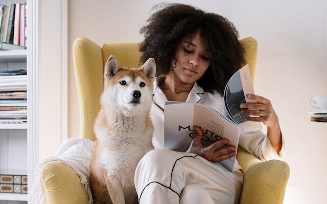 Eine Frau, die eine Zeitschrift liest, mit ihrem Hund neben sich 
